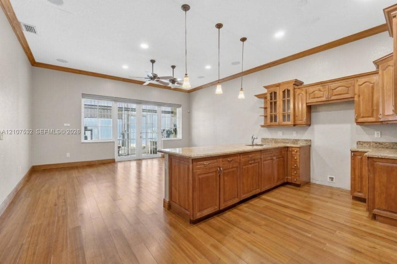 9124 NW 147th Terrace, Miami Lakes, FL 33018 Kitchen featuring wood-finish cabinetry, stone countertops, pendant lighting, recessed lighting, and wood-finish flooring