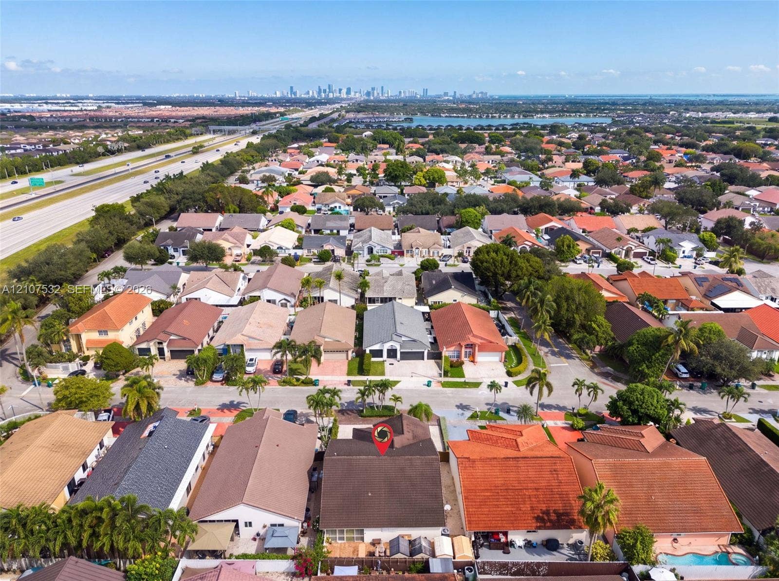 9124 NW 147th Terrace, Miami Lakes, FL 33018 Aerial perspective of a residential property featuring a pitched shingle roof, mature perimeter landscaping, and a fenced rear yard