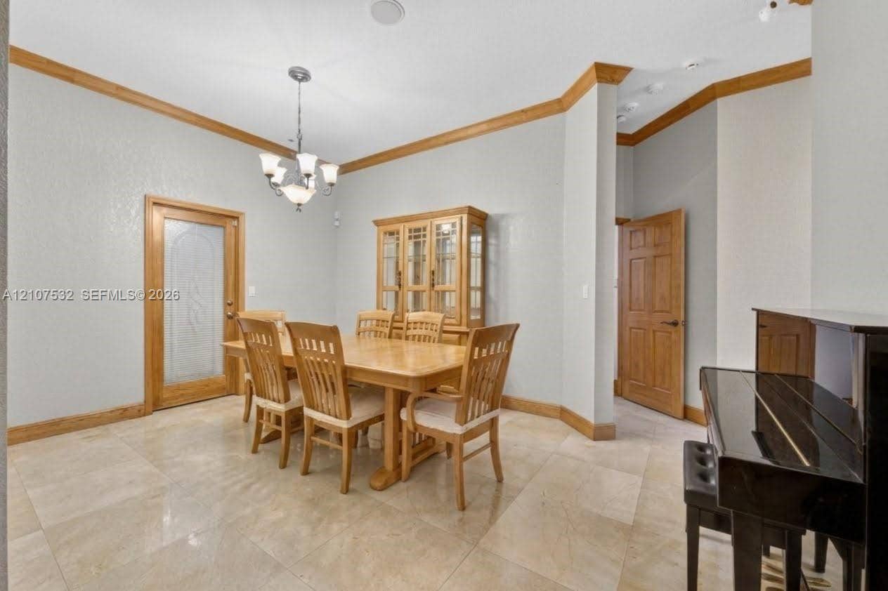 9124 NW 147th Terrace, Miami Lakes, FL 33018 Stone tile flooring, crown molding, a decorative glass-panel door, and a multi-arm chandelier