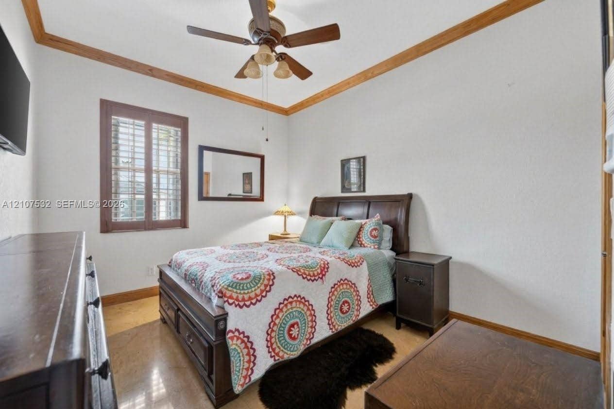 9124 NW 147th Terrace, Miami Lakes, FL 33018 Room featuring wood-finish ceiling crown molding, a central ceiling fan with integrated lighting, polished stone flooring, and window shutter accents
