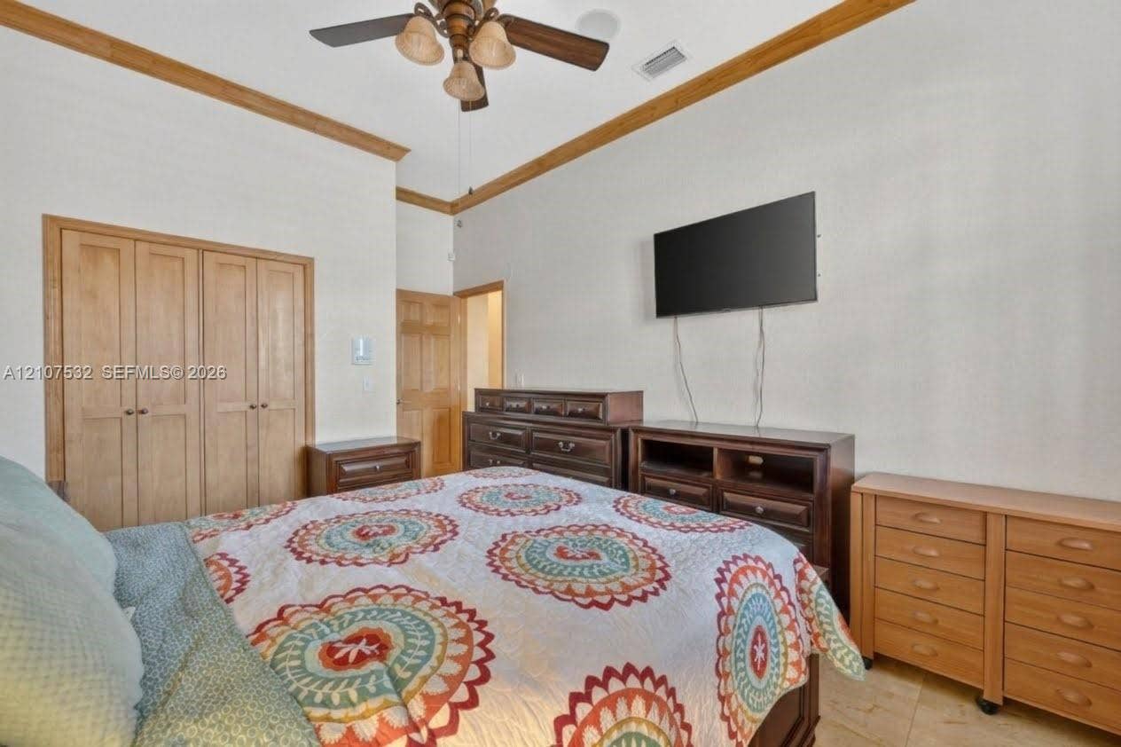 9124 NW 147th Terrace, Miami Lakes, FL 33018 Room featuring crown molding, multi-panel wood doors, tile flooring, and a ceiling fan with integrated lighting