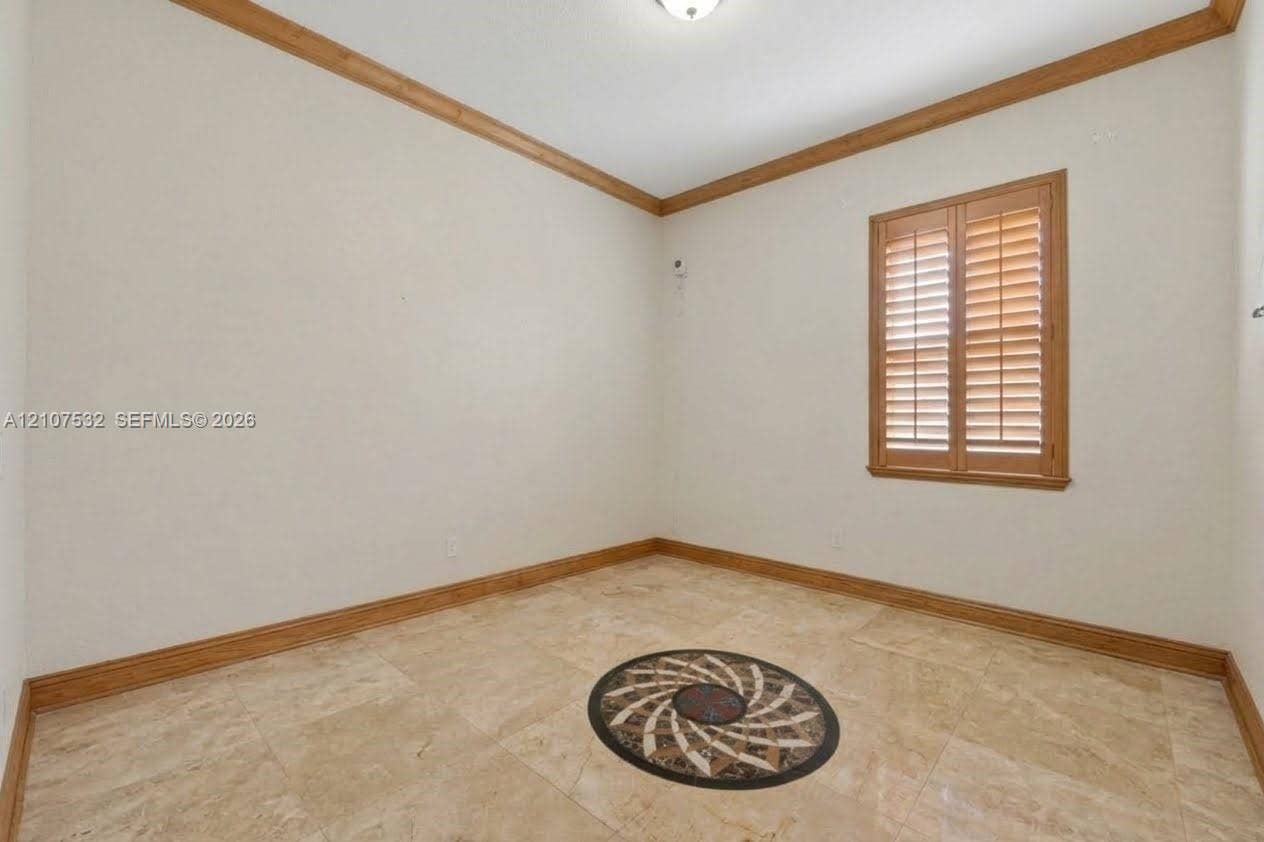 9124 NW 147th Terrace, Miami Lakes, FL 33018 Interior room featuring stone flooring with a circular medallion inlay, crown molding, and plantation shutters