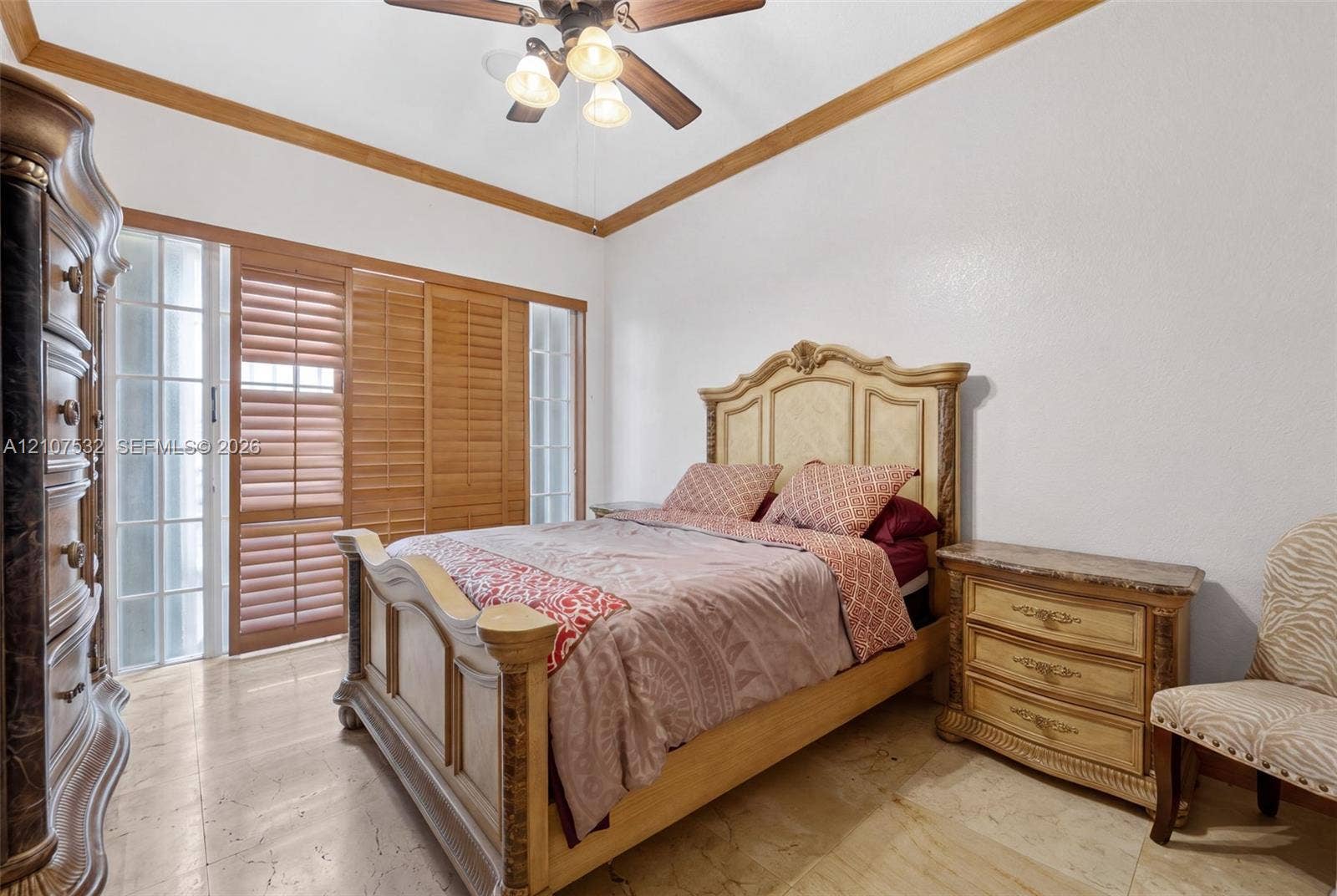 9124 NW 147th Terrace, Miami Lakes, FL 33018 Tray ceiling with crown molding, natural stone flooring, and built-in sliding wood-slat closet doors with sidelight windows