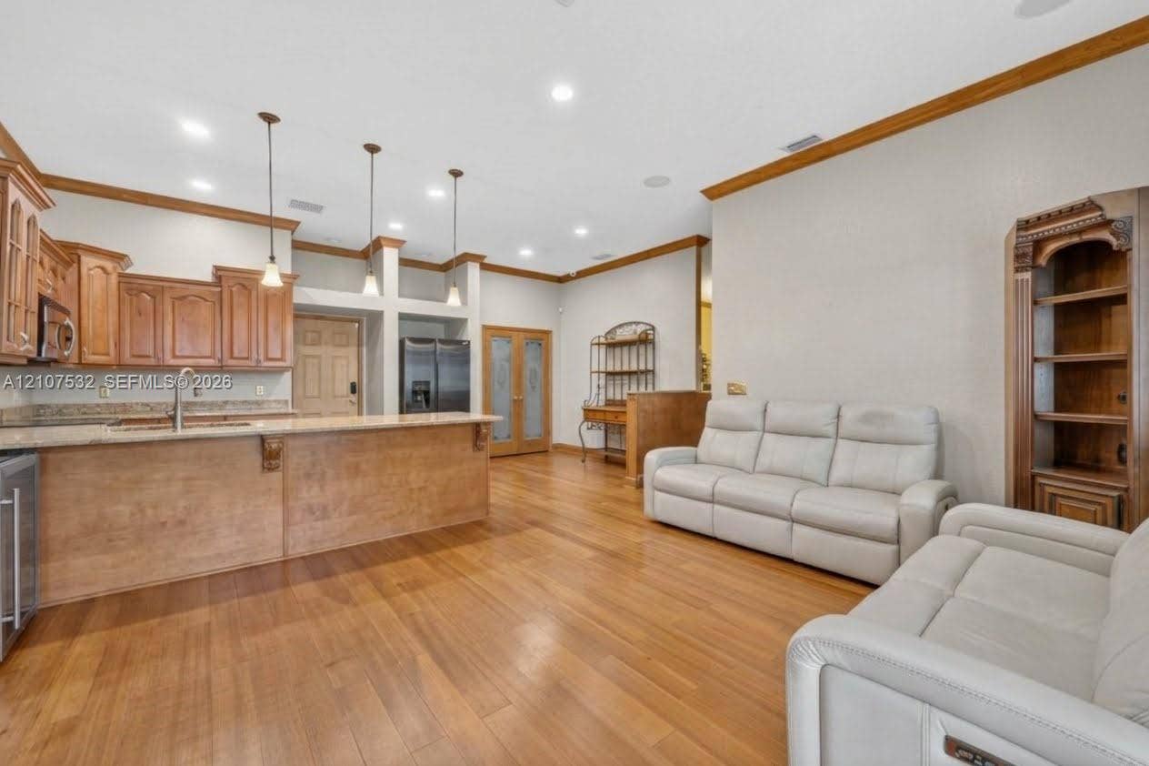 9124 NW 147th Terrace, Miami Lakes, FL 33018 Kitchen featuring wood-finish cabinetry, stone-surface countertops, pendant lighting, built-in shelving, and wood-finish flooring