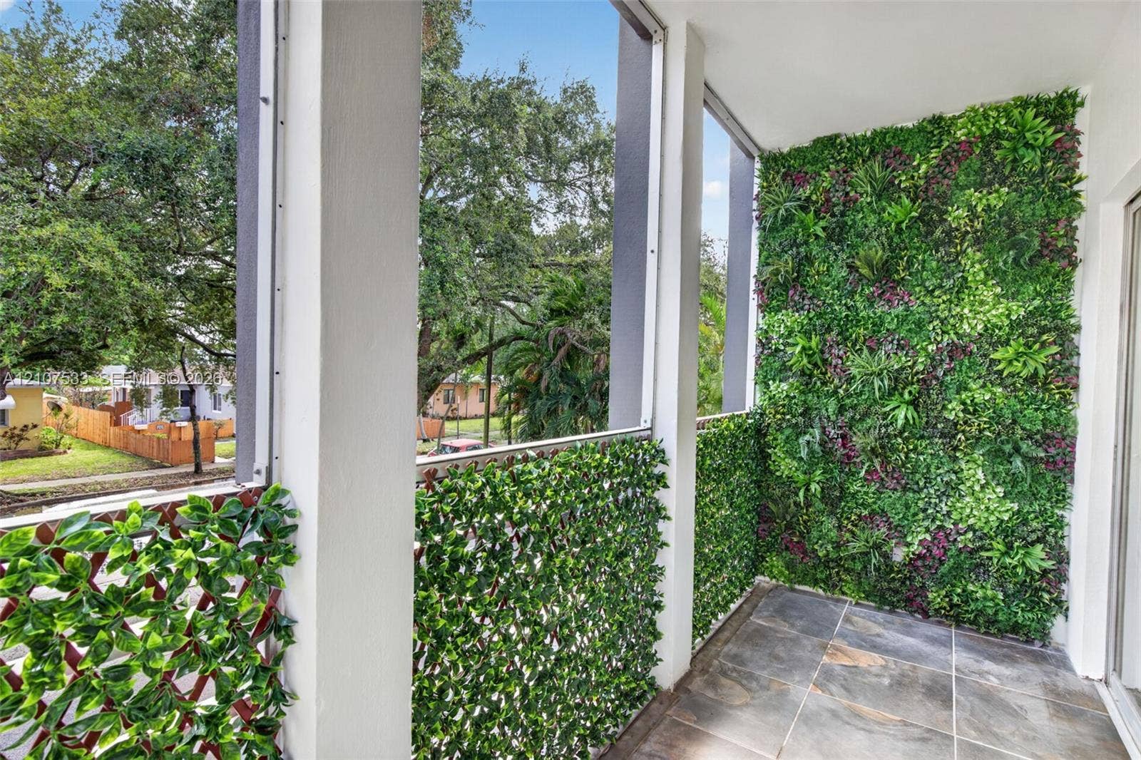 1939 Jefferson Street, #201, Hollywood, Hollywood, FL 33020 Screened balcony featuring slate-finish tile flooring, vertical garden wall, and decorative greenery privacy screening