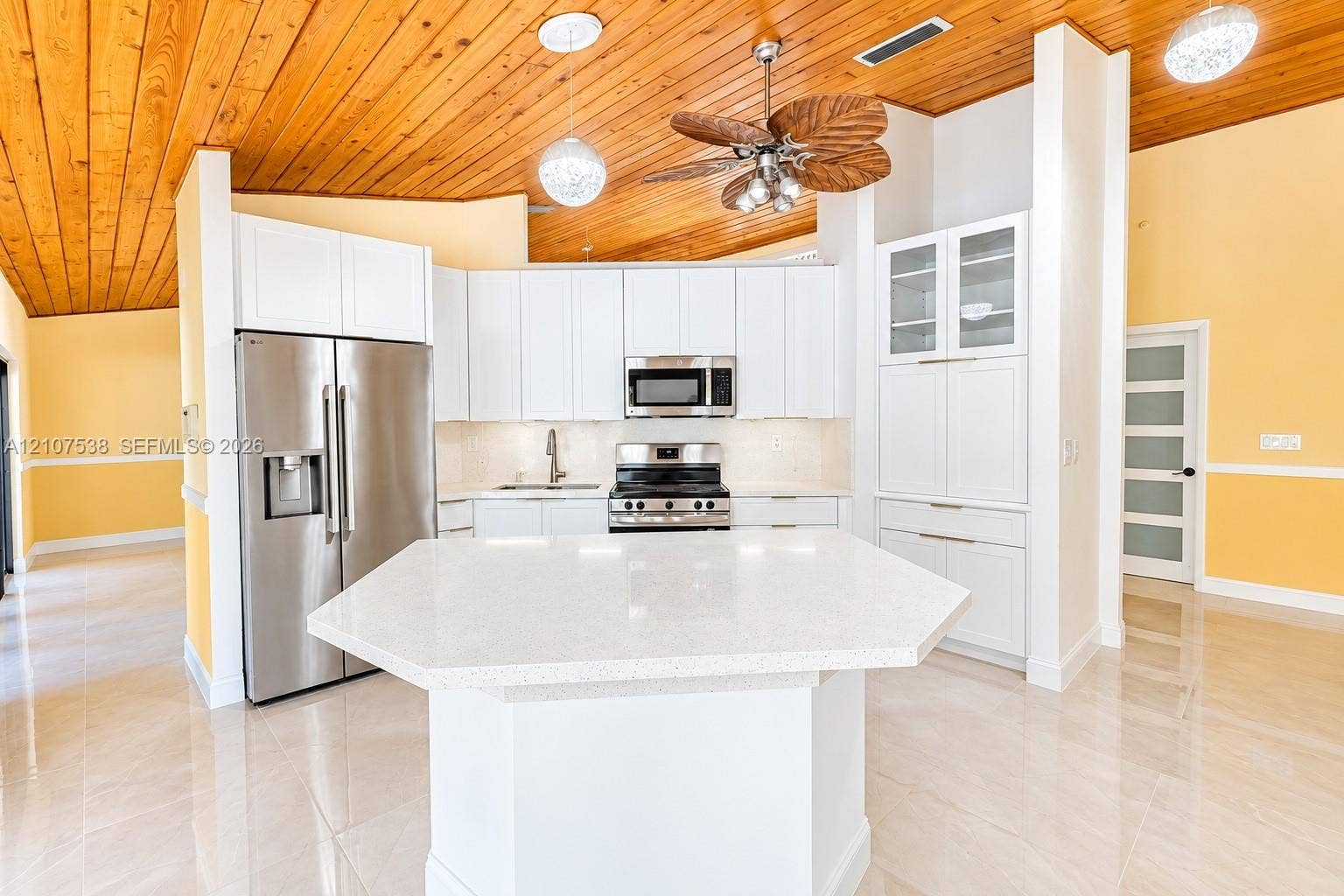 10204 SW 96th Court, Miami, Miami, FL 33176 Kitchen featuring vaulted tongue-and-groove wood ceilings, white shaker cabinetry, stainless steel appliances, a center island with a quartz countertop, and large-format polished tile flooring