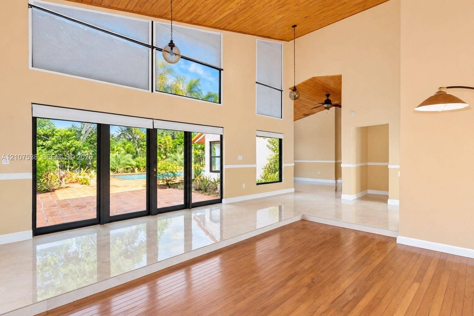 10204 SW 96th Court, Miami, Miami, FL 33176 Vaulted wood-plank ceiling, floor-to-ceiling windows, polished tile flooring, wood-finish flooring, and multi-panel sliding glass doors