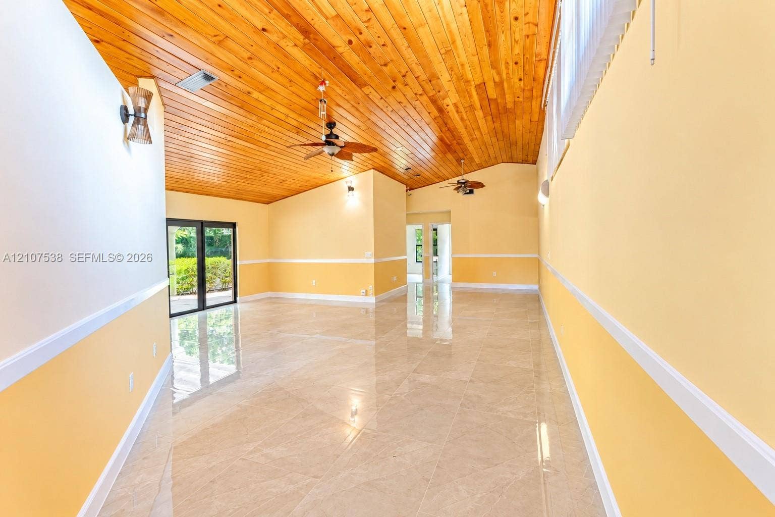 10204 SW 96th Court, Miami, Miami, FL 33176 Vaulted wood-plank ceiling featuring integrated ceiling fans, large-format tile flooring, chair rail molding, and sliding glass doors
