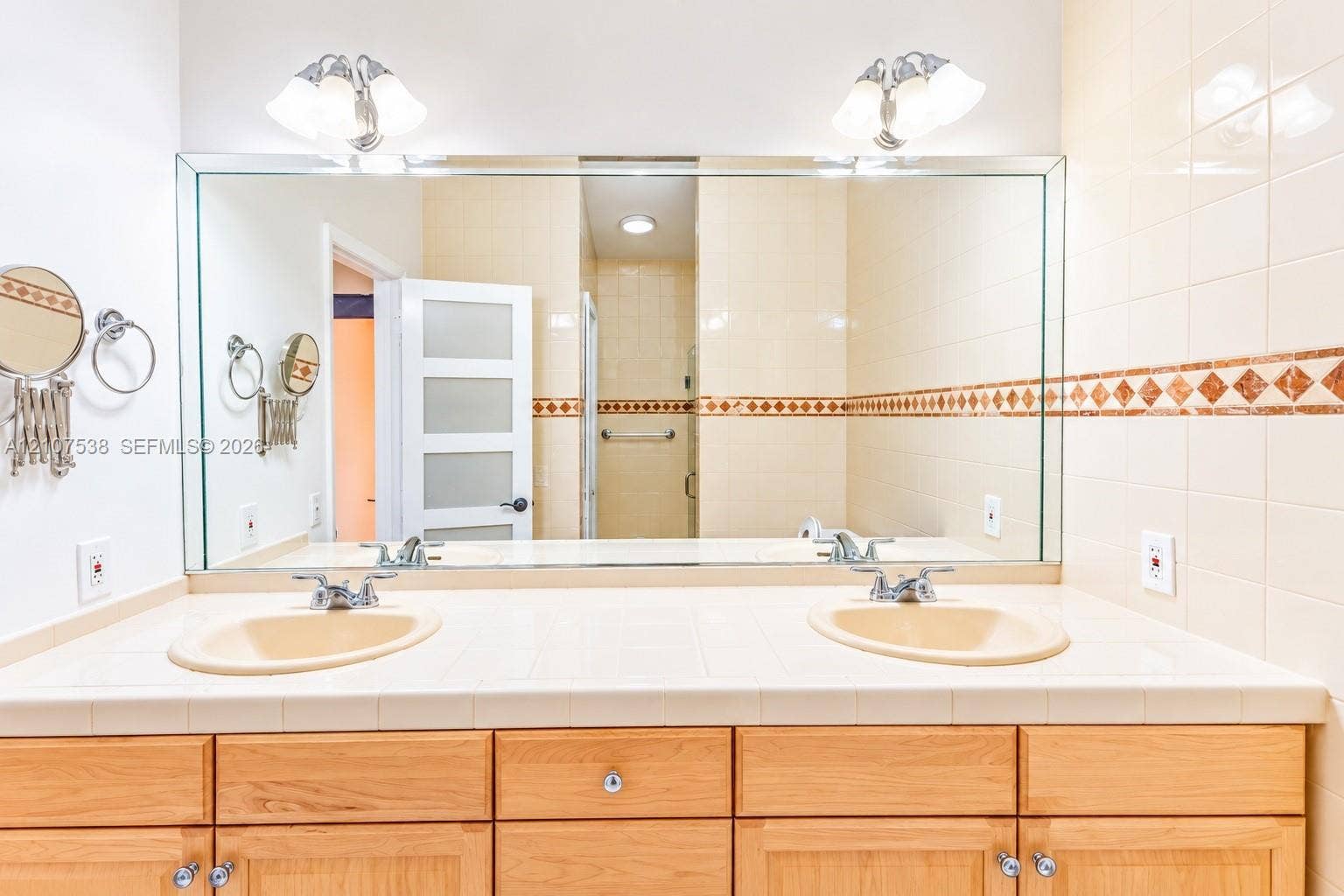 10204 SW 96th Court, Miami, Miami, FL 33176 Dual-sink vanity with a tile countertop, large wall-mounted mirror, light wood cabinetry, and decorative tile backsplash