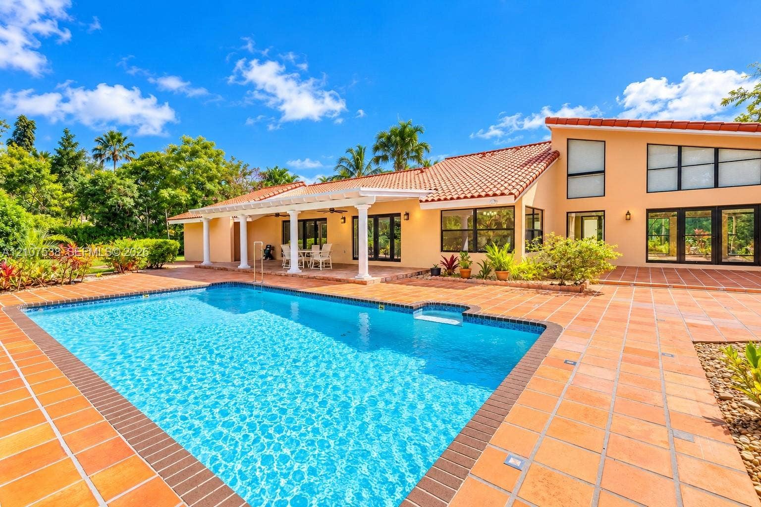 10204 SW 96th Court, Miami, Miami, FL 33176 Swimming pool with a tile surround and a covered patio featuring structural columns, terracotta roof tiles, and multi-paned windows