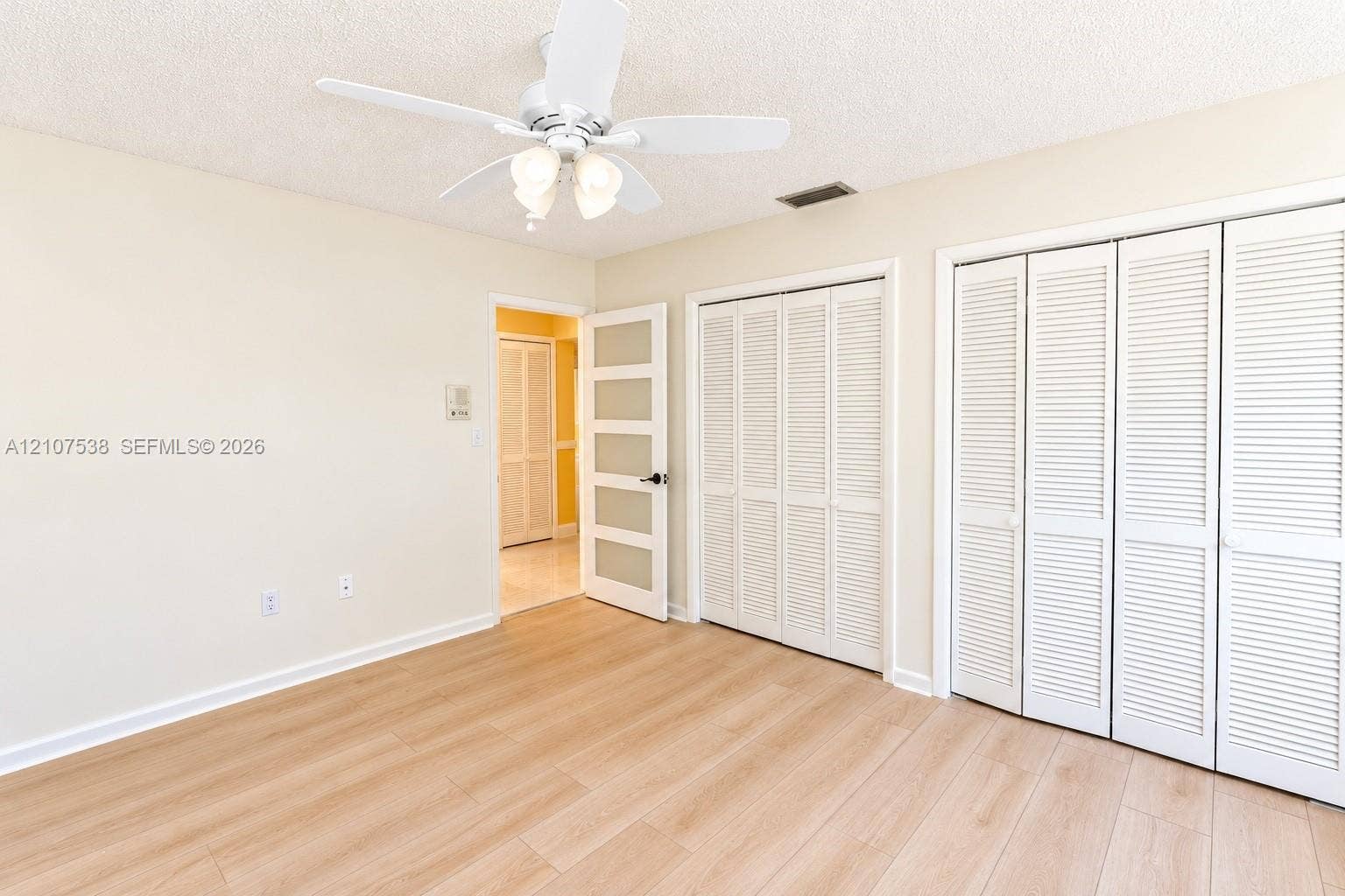 10204 SW 96th Court, Miami, Miami, FL 33176 Room featuring light-toned wood-finish flooring, a white ceiling fan with integrated lighting, dual sets of white louvered closet doors, and a four-panel interior door