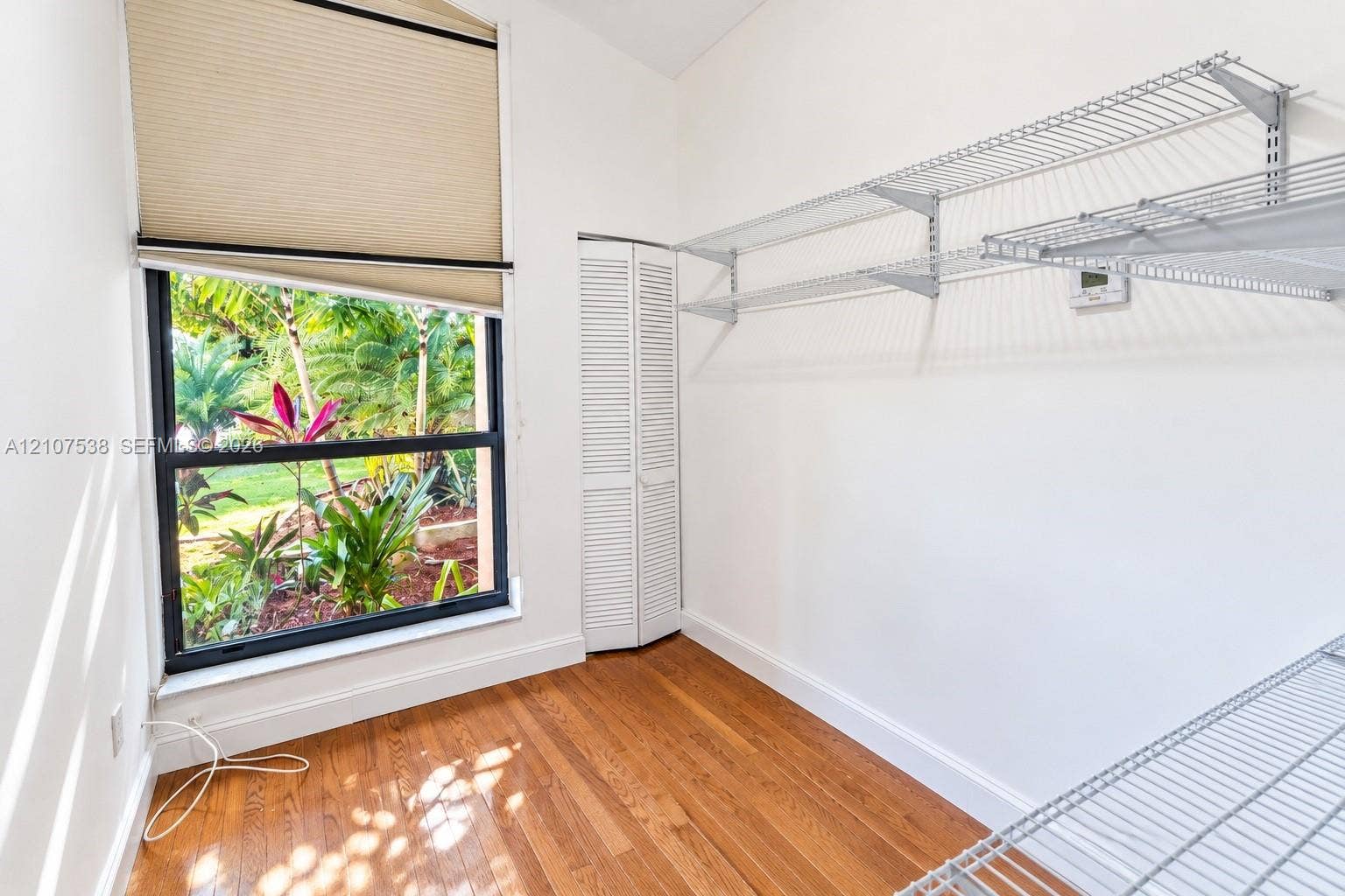 10204 SW 96th Court, Miami, Miami, FL 33176 Wood-finish flooring, white louvered-panel closet door, multi-level wire shelving, and floor-to-ceiling window with natural landscape exposure