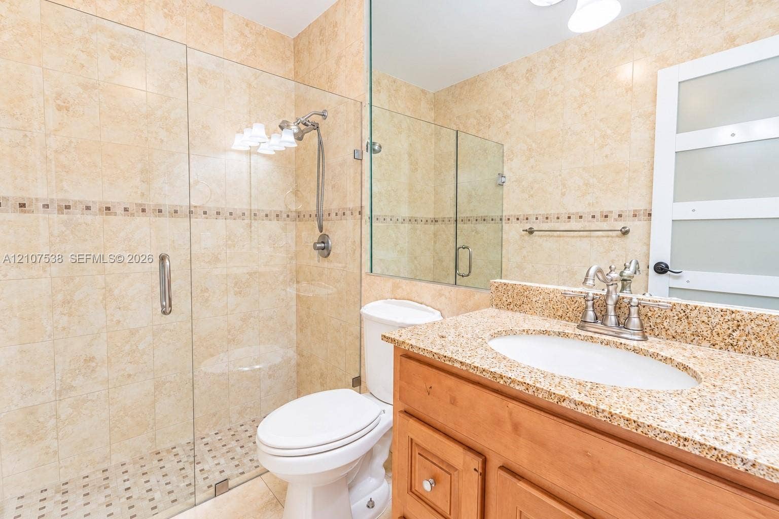 10204 SW 96th Court, Miami, Miami, FL 33176 Bathroom featuring a vanity with stone-finish countertop and undermount sink, walk-in shower with glass enclosure, wall-mounted faucet hardware, and tile wall finishes