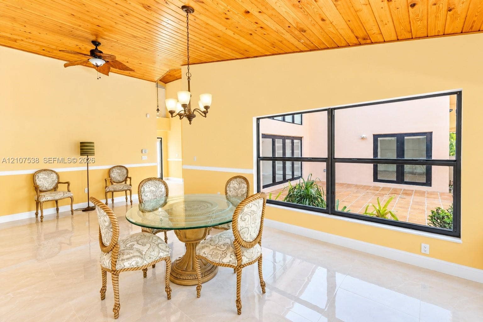 10204 SW 96th Court, Miami, Miami, FL 33176 Vaulted wood-plank ceiling, polished tile flooring, prominent multi-pane window, and decorative hanging chandelier
