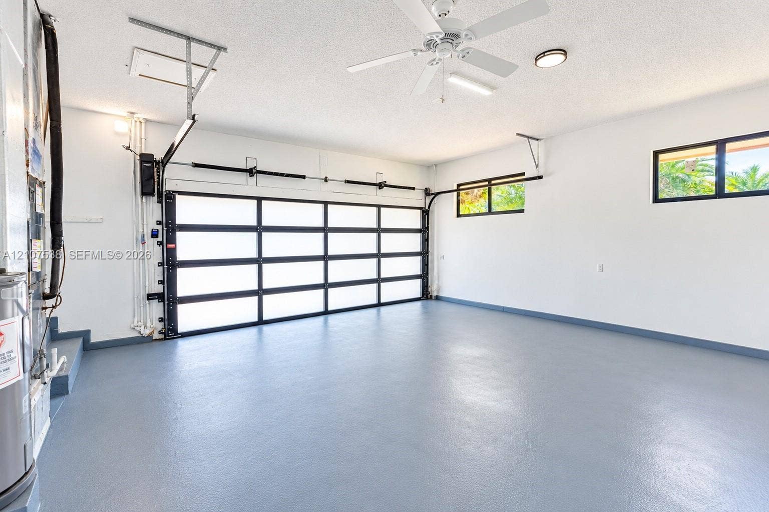10204 SW 96th Court, Miami, Miami, FL 33176 Multi-pane glass panel garage door, epoxy-coated concrete flooring, ceiling-mounted paddle fan, and dual high-set windows