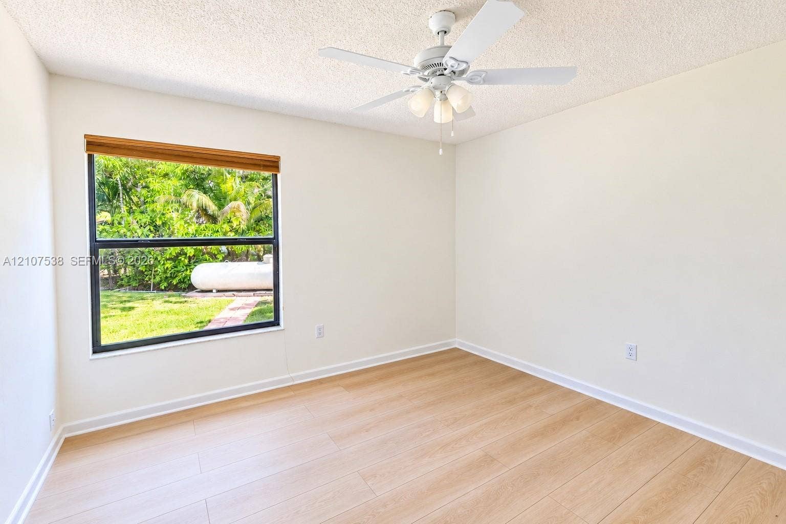 10204 SW 96th Court, Miami, Miami, FL 33176 Interior space featuring wood-finish flooring, a ceiling fan with integrated three-light fixture, and a single-pane window with a woven wood blind