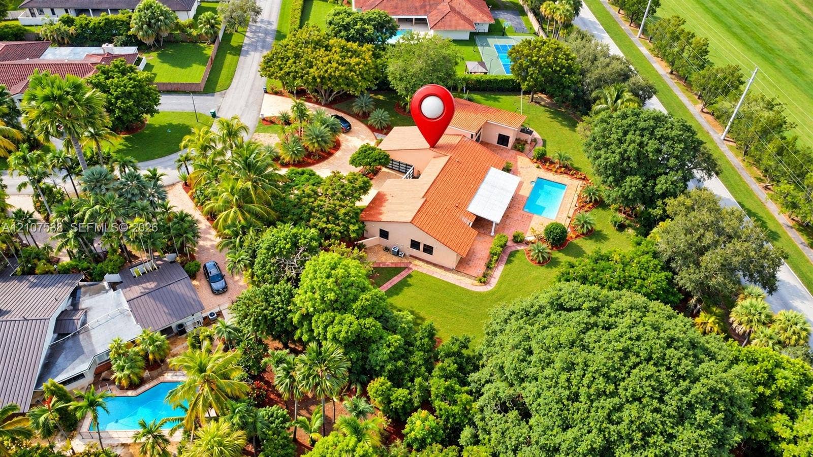 10204 SW 96th Court, Miami, Miami, FL 33176 Aerial perspective of a single-story residence featuring a terracotta-tiled roof, an attached pool, a concrete driveway, and established landscaping