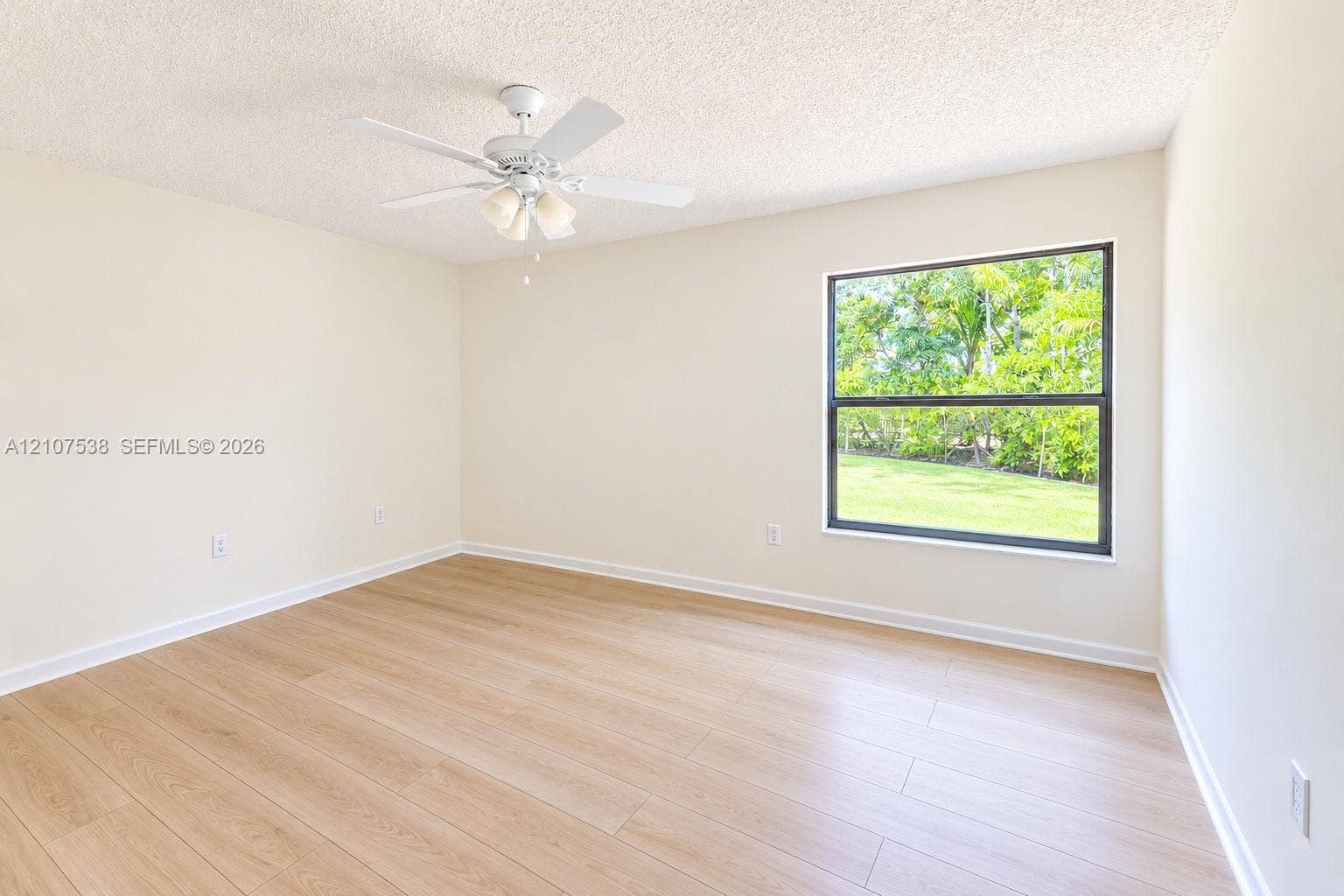 10204 SW 96th Court, Miami, Miami, FL 33176 Neutral-toned interior featuring wood-finish flooring, a white ceiling fan with integrated lighting, and a large single-pane window