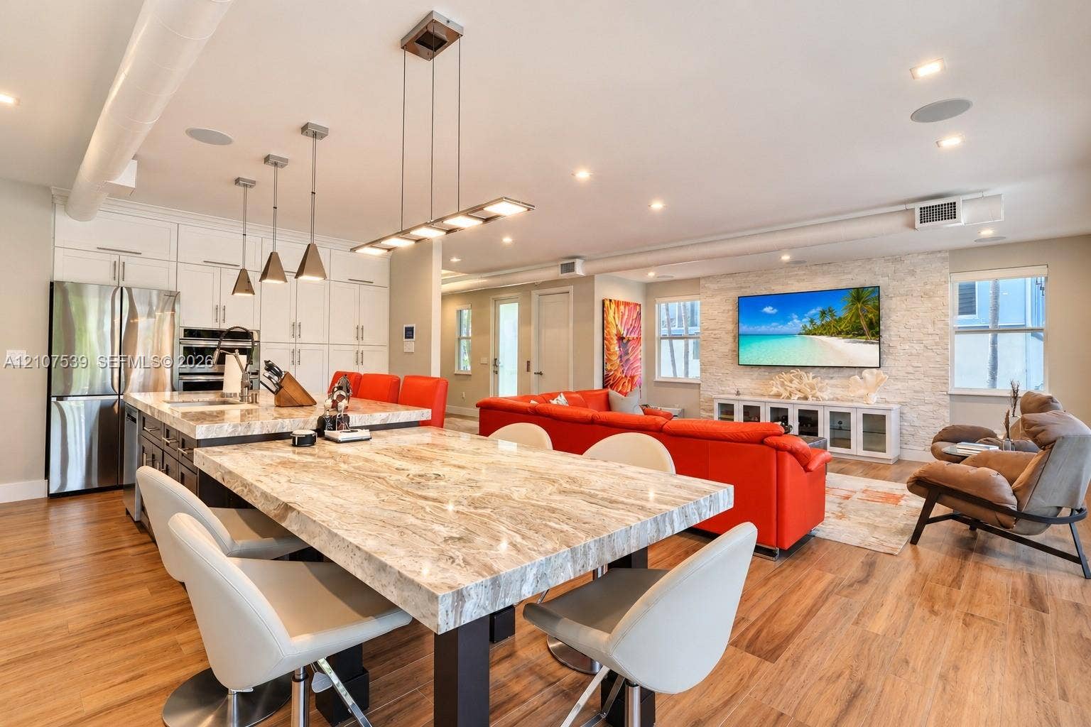 20 Center Lane, Key Largo, FL 33037 Open-concept interior featuring stone-surface island seating, stainless steel appliances, stacked-stone accent wall, recessed lighting, and wood-finish flooring