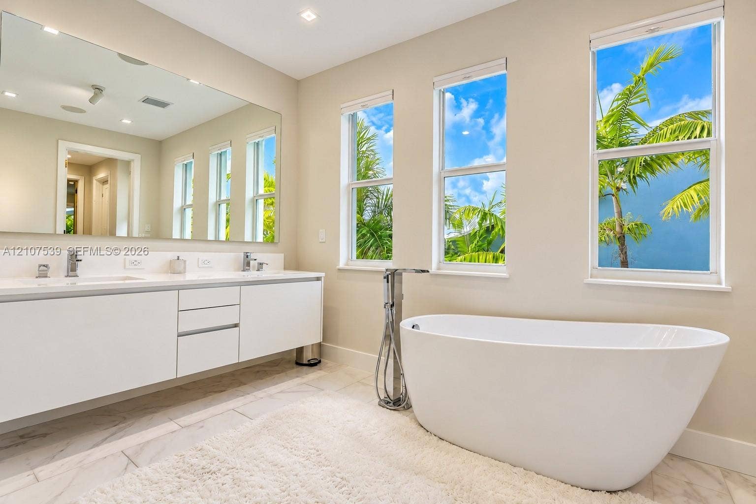 20 Center Lane, Key Largo, FL 33037 Floating vanity with dual rectangular sinks, oversized frameless wall mirror, freestanding soaking tub, chrome floor-mounted tub filler, and tile flooring