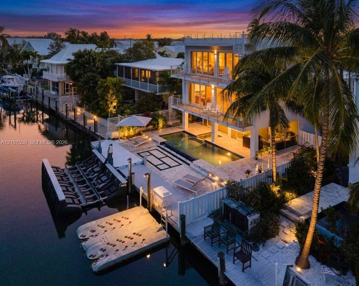 20 Center Lane, Key Largo, FL 33037 Three-story waterfront residence featuring multi-level balconies, a stone-surround swimming pool, and a private dock with boat lift