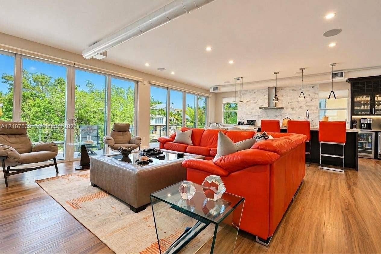 20 Center Lane, Key Largo, FL 33037 Open-concept interior featuring wood-finish flooring, floor-to-ceiling glass sliding doors, recessed lighting, exposed industrial-style ductwork, and a stone-tiled backsplash in the kitchen