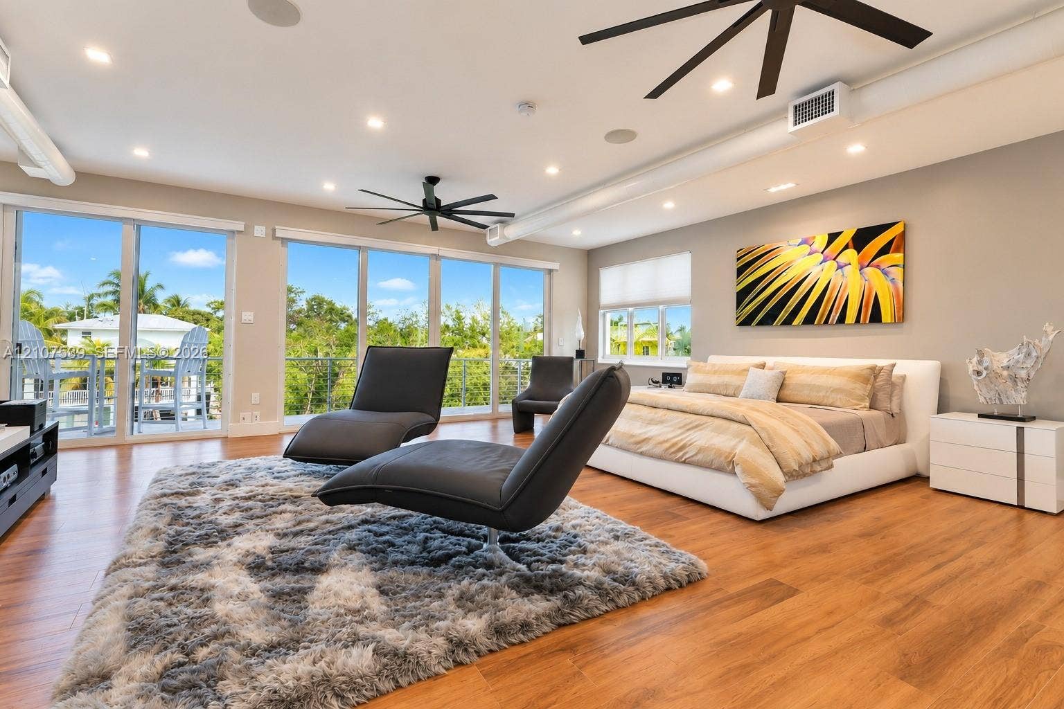 20 Center Lane, Key Largo, FL 33037 Open-concept interior featuring wood-finish flooring, floor-to-ceiling glass sliding doors, recessed lighting, matte black ceiling fans, and exposed ductwork