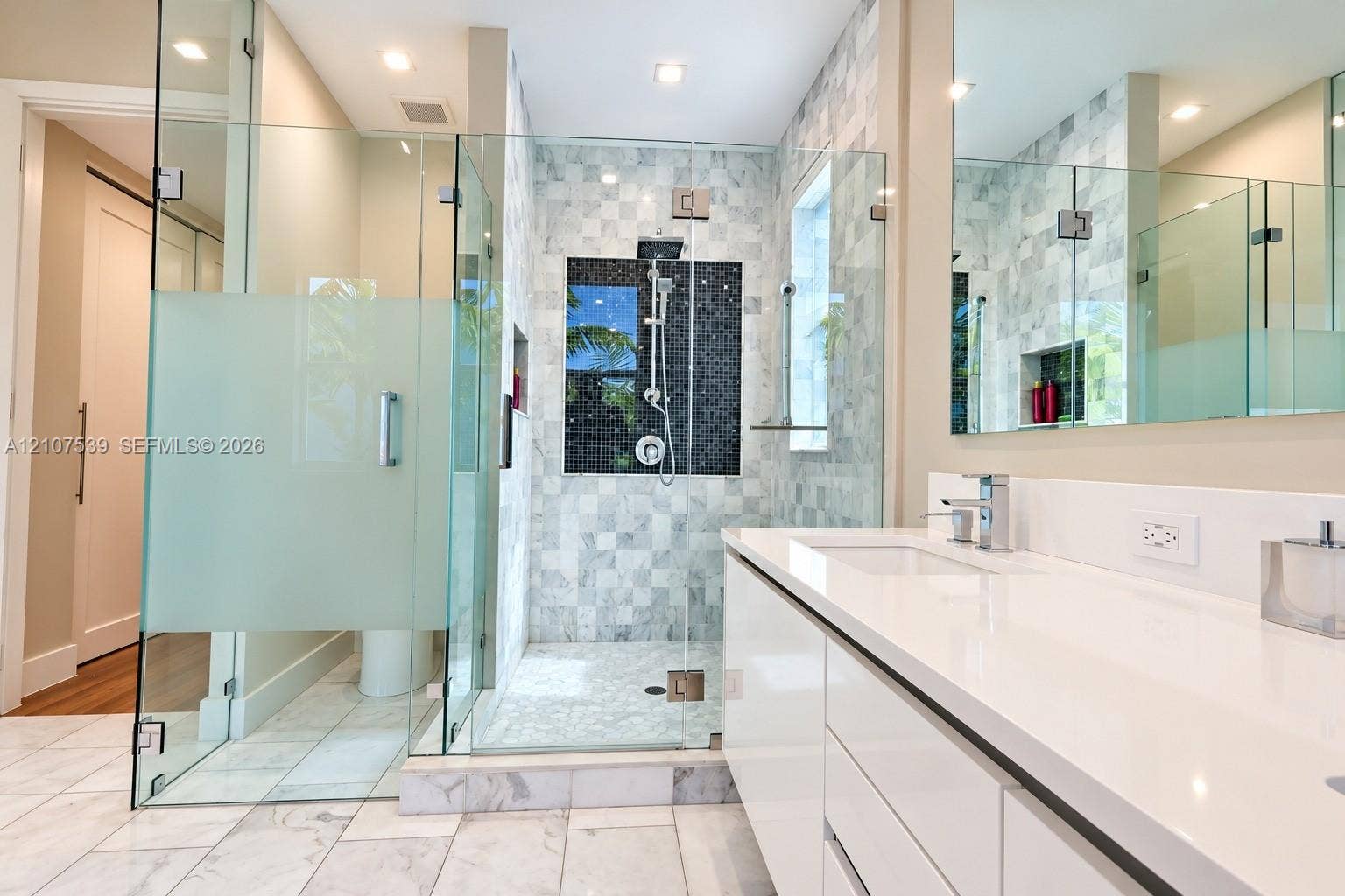 20 Center Lane, Key Largo, FL 33037 Bathroom featuring a white flat-panel vanity with a stone countertop, a glass-enclosed walk-in shower with tiled walls and a built-in recessed niche, and polished stone flooring