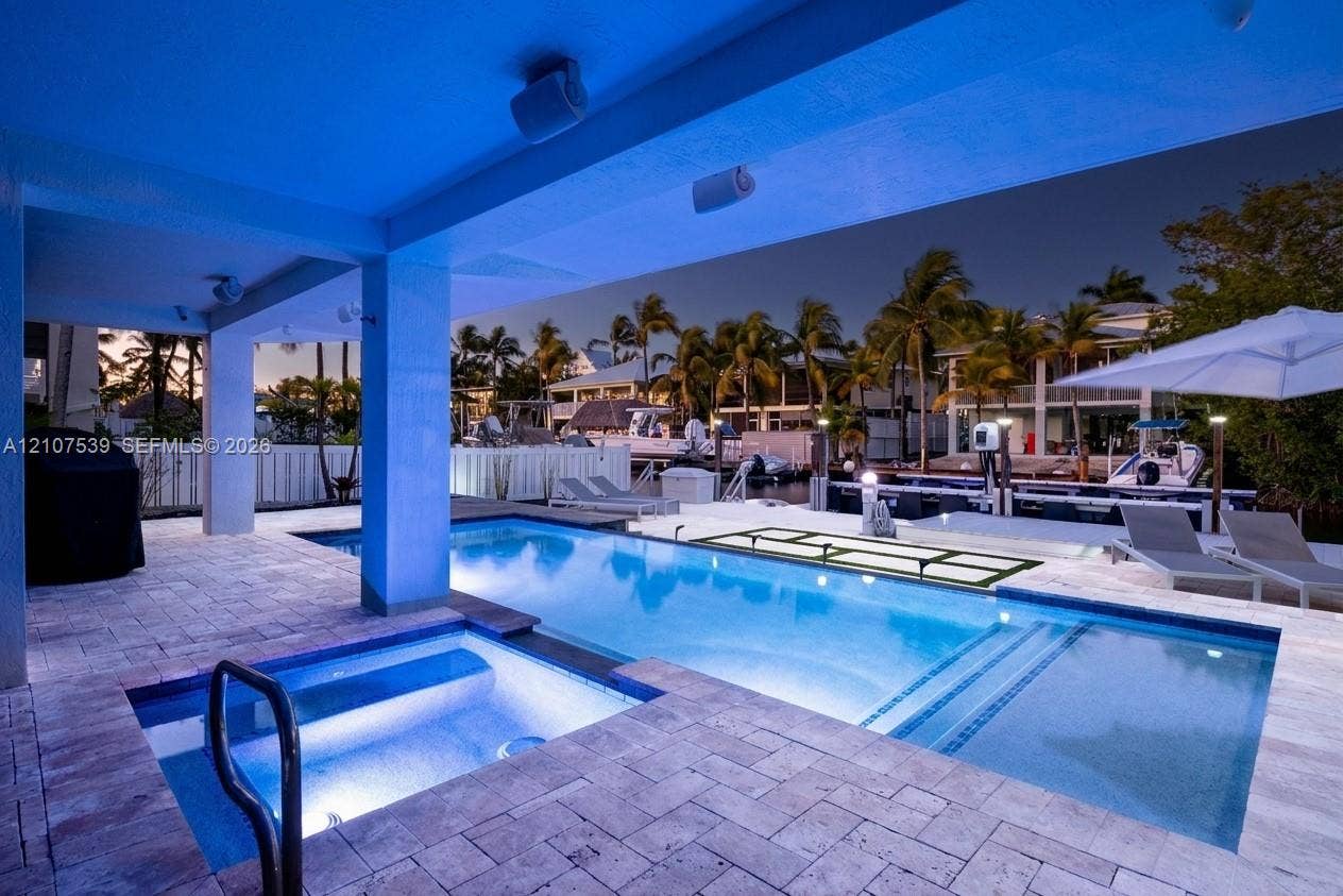 20 Center Lane, Key Largo, FL 33037 Covered outdoor patio featuring stone paver decking, an integrated spa, a rectangular swimming pool, and direct canal access
