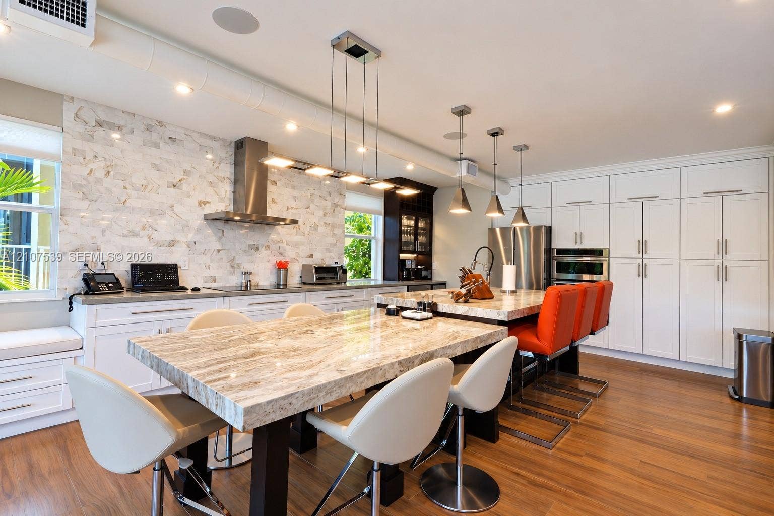 20 Center Lane, Key Largo, FL 33037 Kitchen featuring stone-topped islands, a floor-to-ceiling cabinetry wall, a natural stone tile backsplash, stainless steel appliances, and wood-finish flooring