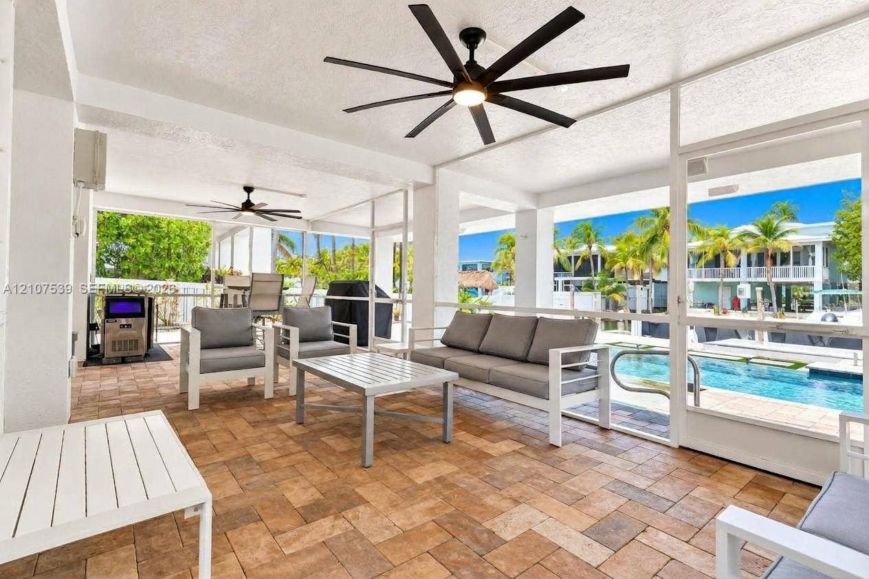 20 Center Lane, Key Largo, FL 33037 Screened-in lanai featuring paver flooring, multiple multi-blade ceiling fans, and a direct perimeter enclosure overlooking the pool area
