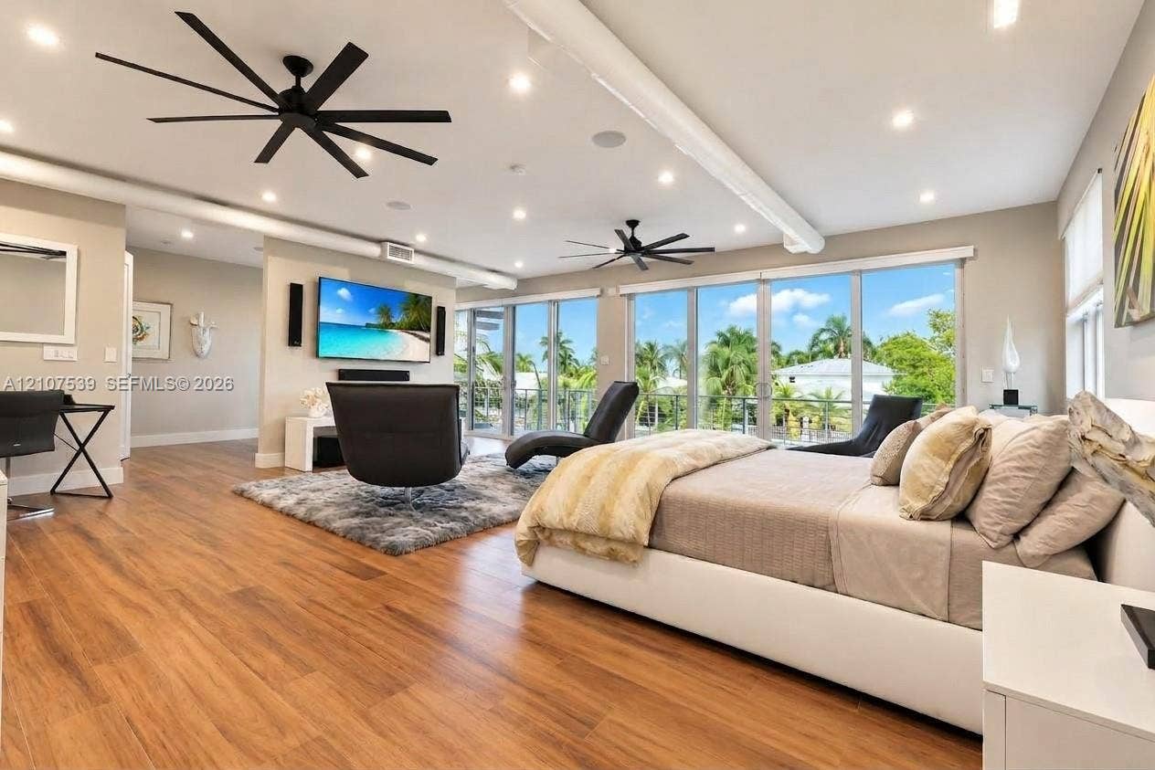 20 Center Lane, Key Largo, FL 33037 Wood-finish flooring, floor-to-ceiling glass wall, recessed lighting, matte black multi-blade ceiling fans, and built-in wall-mounted television console
