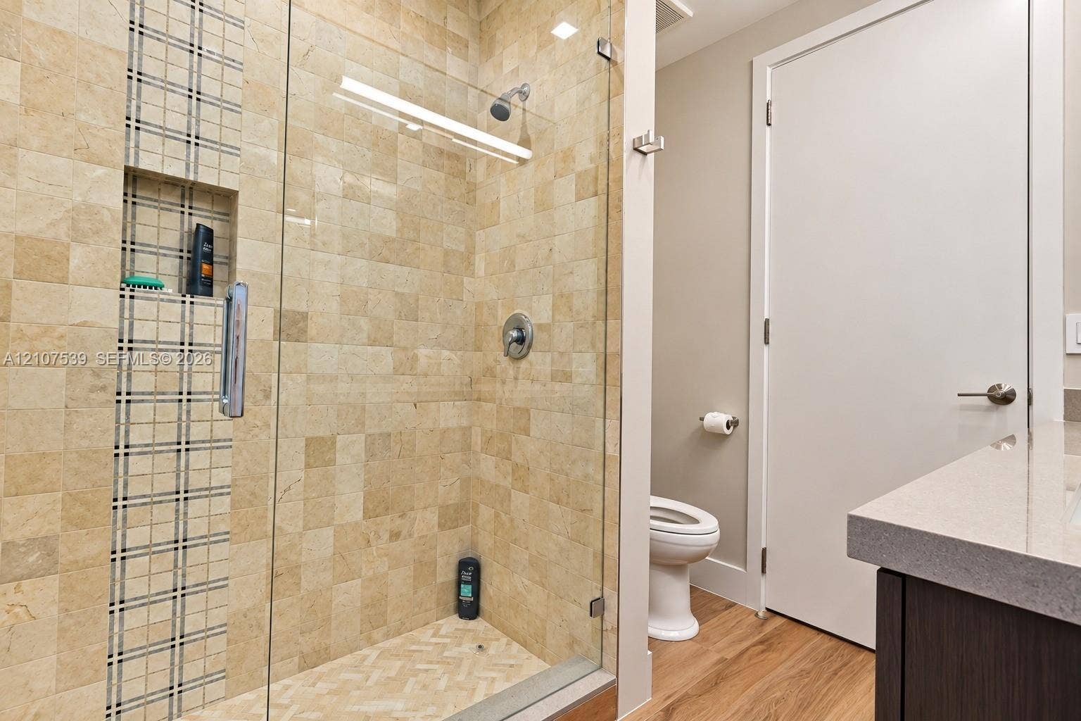 20 Center Lane, Key Largo, FL 33037 Walk-in shower with square stone tiling, built-in vertical mosaic accent niche, frameless glass door, and a solid-surface vanity countertop