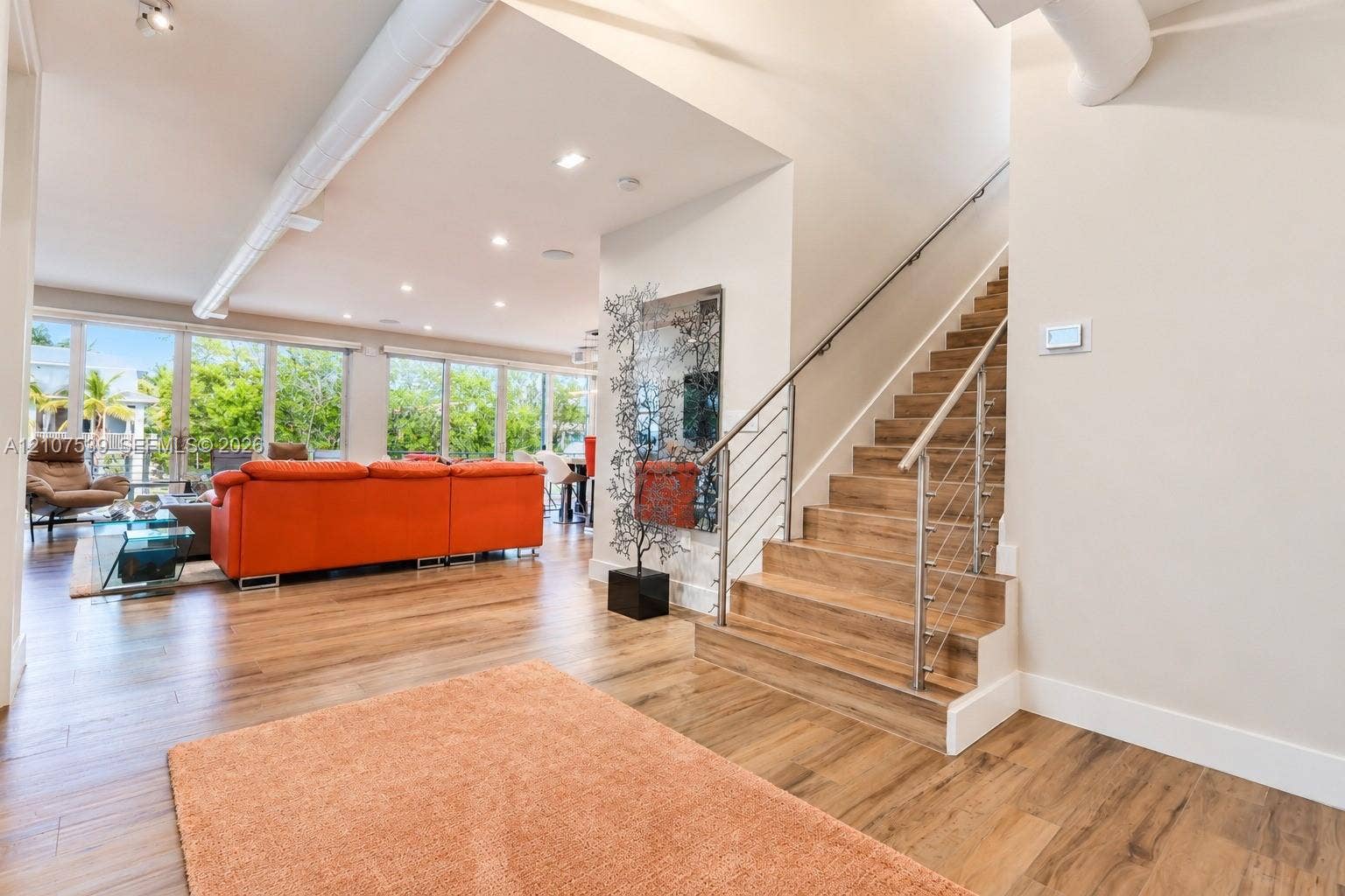 20 Center Lane, Key Largo, FL 33037 Open floor plan featuring wood-finish flooring, floor-to-ceiling windows, exposed industrial ductwork, recessed lighting, and a staircase with cable railings and wood-finish treads