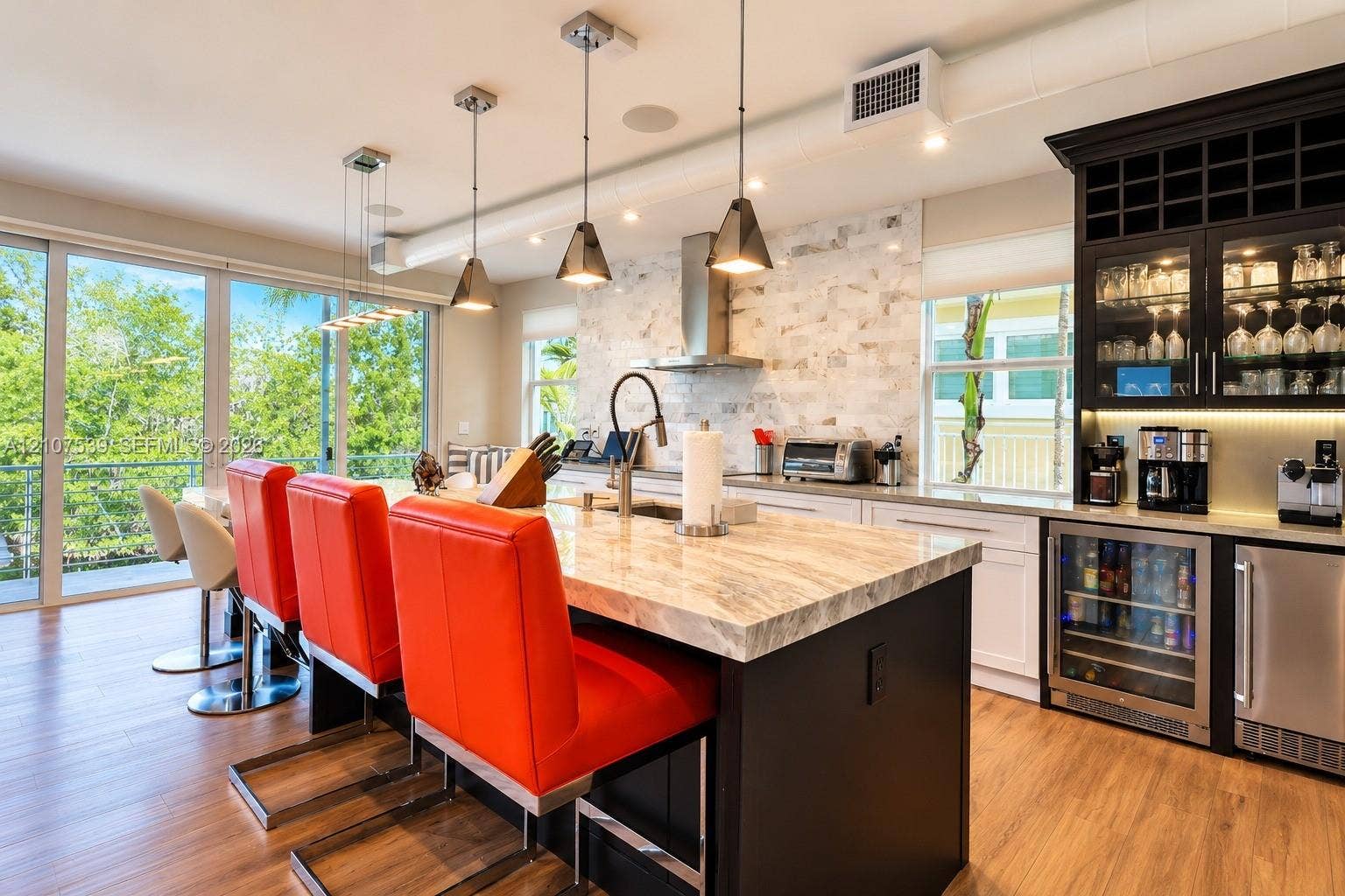 20 Center Lane, Key Largo, FL 33037 Kitchen featuring a spacious island with stone-finish countertops, custom cabinetry with integrated wine storage, a stainless steel range hood, stone-style backsplash, and wood-finish flooring