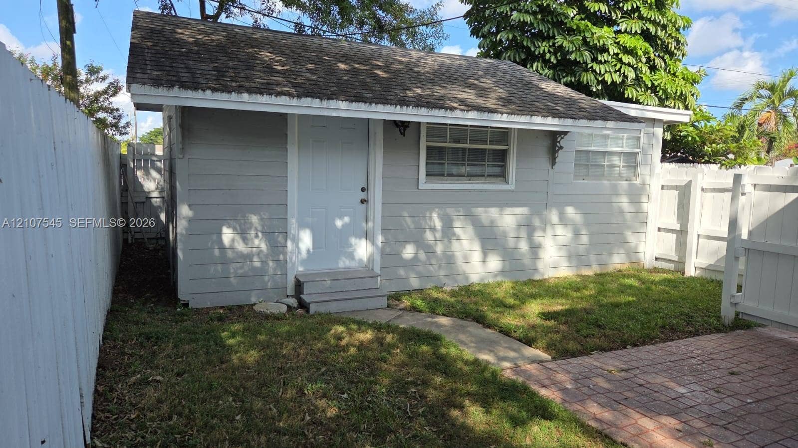 6431 Hayes Street, #3, Hollywood, Hollywood, FL 33024 Detached structure featuring horizontal siding, a pitched roof, decorative eave brackets, and a brick paver patio set within a fenced yard