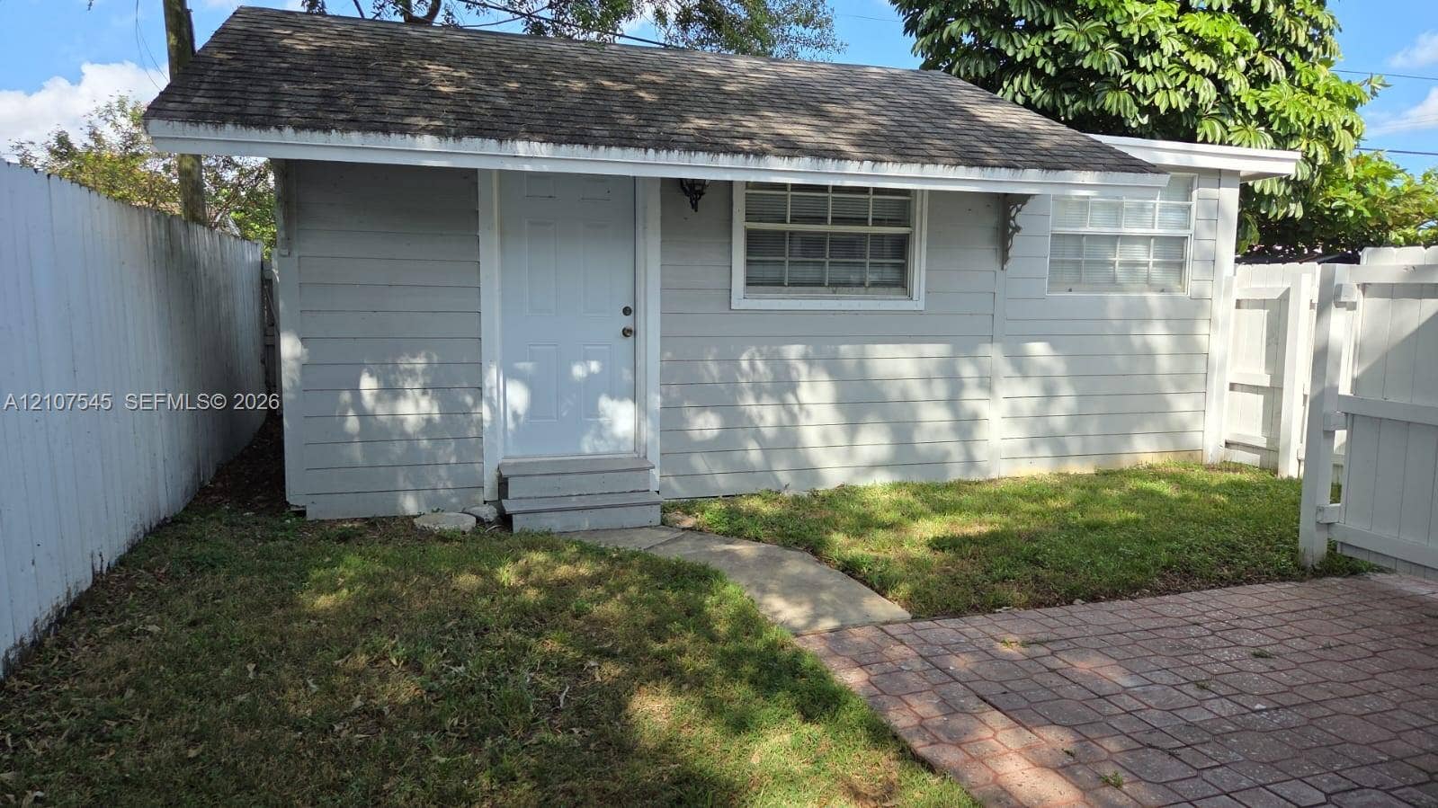 6431 Hayes Street, #3, Hollywood, Hollywood, FL 33024 Detached structure featuring horizontal siding, a pitched roof, multi-pane windows, and a paved brick patio