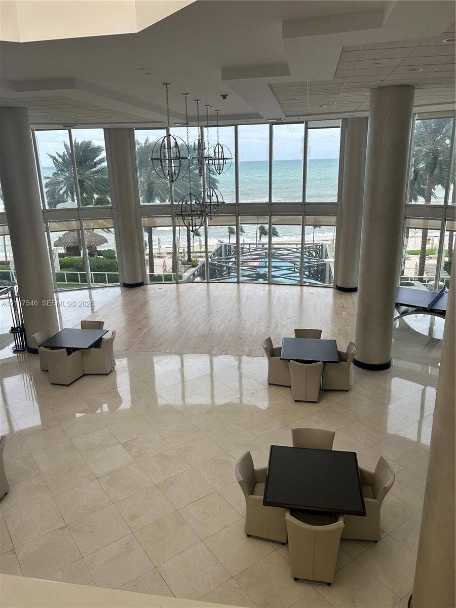 19333 Collins Avenue, #2007, Sunny Isles Beach, Sunny Isles Beach, FL 33160 Double-height floor-to-ceiling windows, polished tile flooring, wood-finish flooring accents, structural cylindrical columns, and metal orb pendant lighting