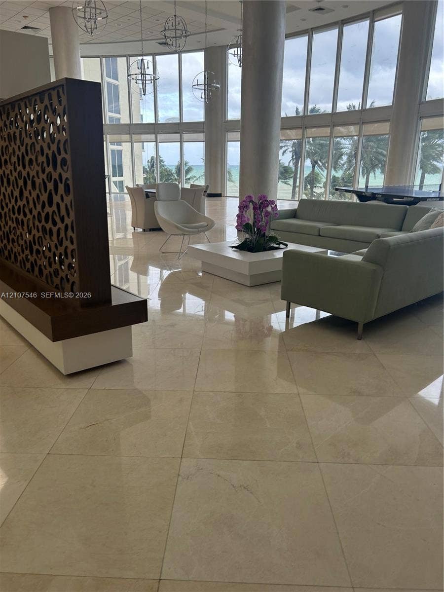19333 Collins Avenue, #2007, Sunny Isles Beach, Sunny Isles Beach, FL 33160 Grand lobby featuring floor-to-ceiling windows, polished stone flooring, custom decorative wood partition, and spherical pendant lighting