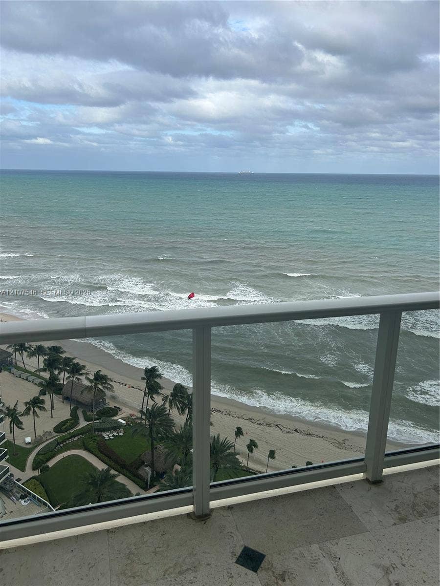 19333 Collins Avenue, #2007, Sunny Isles Beach, Sunny Isles Beach, FL 33160 Balcony featuring stone tile flooring and a glass-paneled railing overlooking the ocean coastline