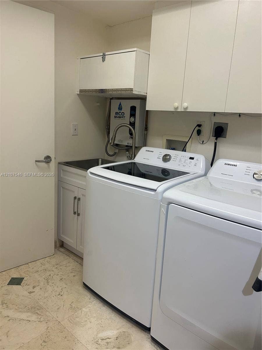 19333 Collins Avenue, #2007, Sunny Isles Beach, Sunny Isles Beach, FL 33160 Utility area featuring white shaker-style cabinetry, wall-mounted storage units, a stainless steel sink with a high-arc pull-down faucet, and stone flooring