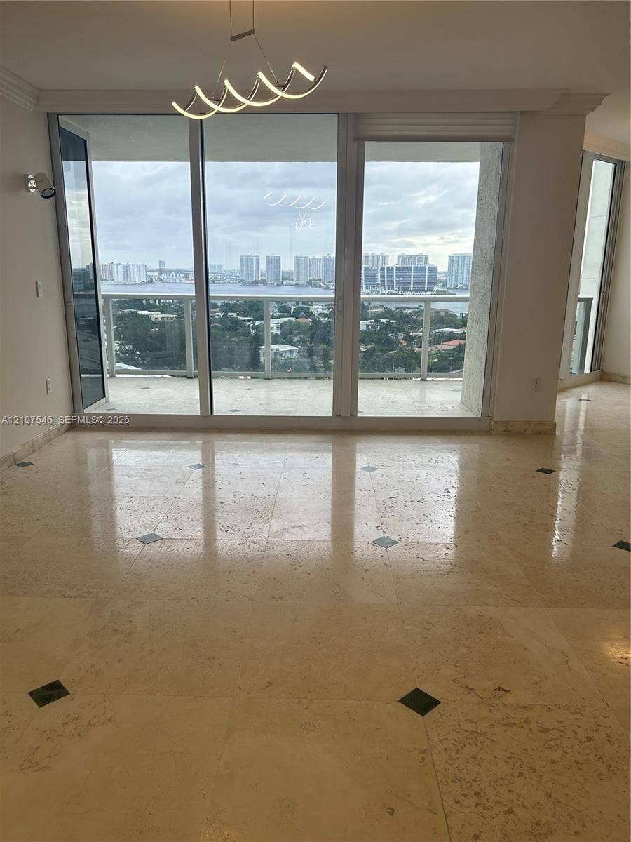19333 Collins Avenue, #2007, Sunny Isles Beach, Sunny Isles Beach, FL 33160 Polished stone flooring with decorative inlays, expansive floor-to-ceiling glass sliding doors, private balcony, contemporary geometric pendant lighting, and panoramic water and city skyline outlooks