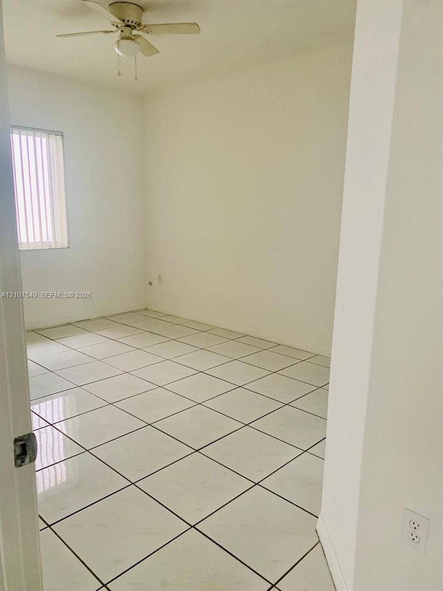 8995 NW 148th Street, #8995, Miami Lakes, Miami Lakes, FL 33018 Room featuring large-format ceramic tile flooring, neutral wall finishes, a ceiling fan with integrated lighting, and vertical blinds on the window