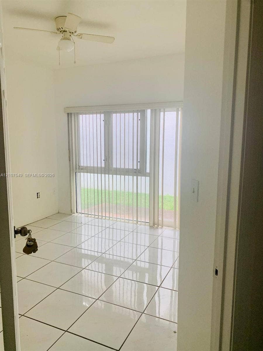 8995 NW 148th Street, #8995, Miami Lakes, Miami Lakes, FL 33018 Interior room featuring white ceramic tile flooring, ceiling fan with integrated light fixture, and floor-to-ceiling windows equipped with vertical blinds