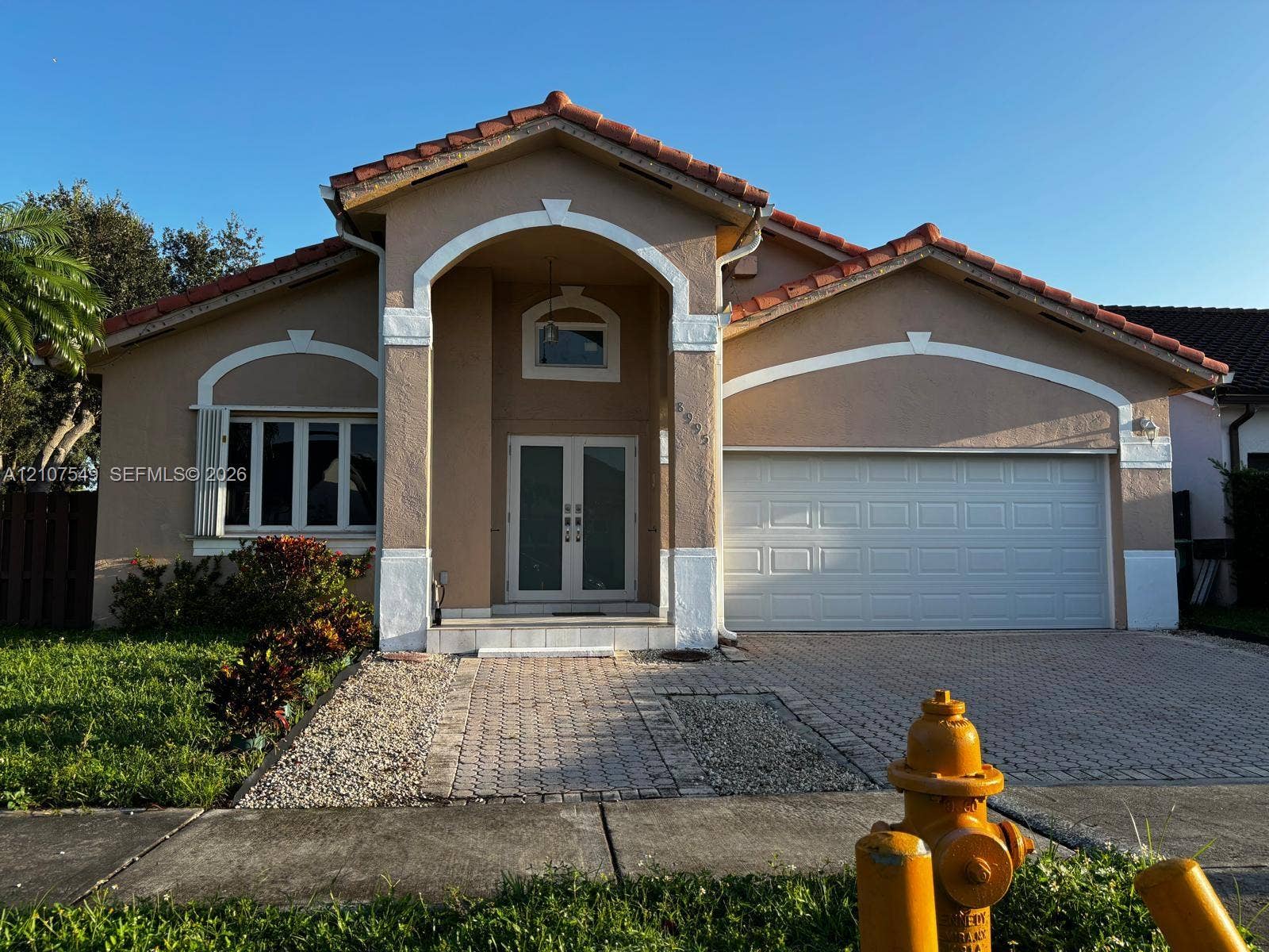 8995 NW 148th Street, #8995, Miami Lakes, Miami Lakes, FL 33018 Stucco exterior with a tiled roof, arched entryway, double-door entrance, and a paved driveway