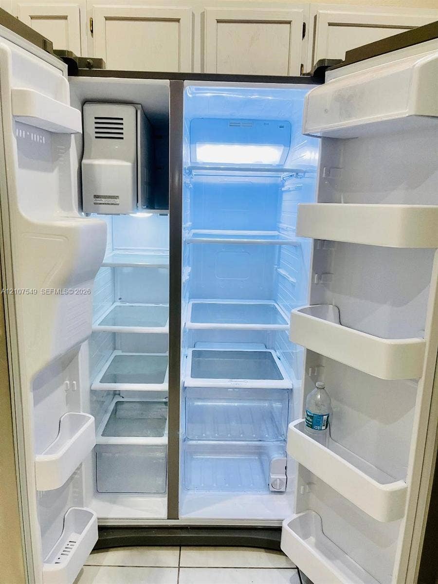 8995 NW 148th Street, #8995, Miami Lakes, Miami Lakes, FL 33018 Side-by-side stainless steel refrigerator featuring adjustable glass shelving, clear crisper drawers, integrated door storage, and a built-in ice dispenser