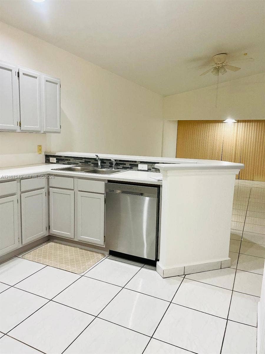 8995 NW 148th Street, #8995, Miami Lakes, Miami Lakes, FL 33018 Kitchen featuring white shaker-style cabinetry, stainless steel dishwasher, dual-basin stainless steel sink, tiled backsplash, and white tile flooring