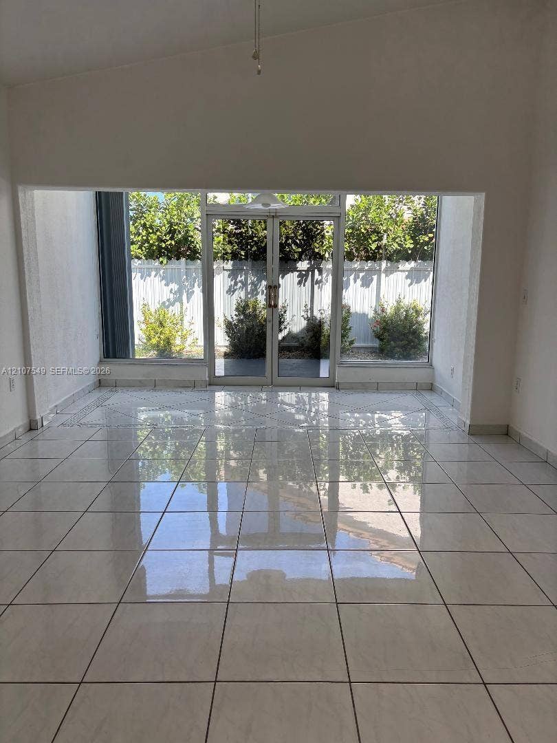 8995 NW 148th Street, #8995, Miami Lakes, Miami Lakes, FL 33018 Open-concept space featuring polished ceramic tile flooring, vaulted ceilings, and expansive glass double doors with flanking floor-to-ceiling windows