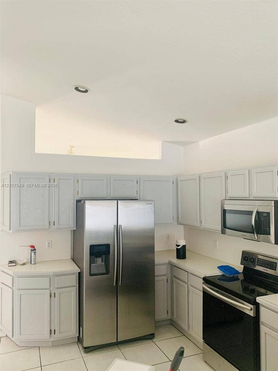 8995 NW 148th Street, #8995, Miami Lakes, Miami Lakes, FL 33018 Kitchen featuring light-toned cabinetry, solid-surface countertops, stainless steel side-by-side refrigerator, built-in microwave, and recessed ceiling lighting