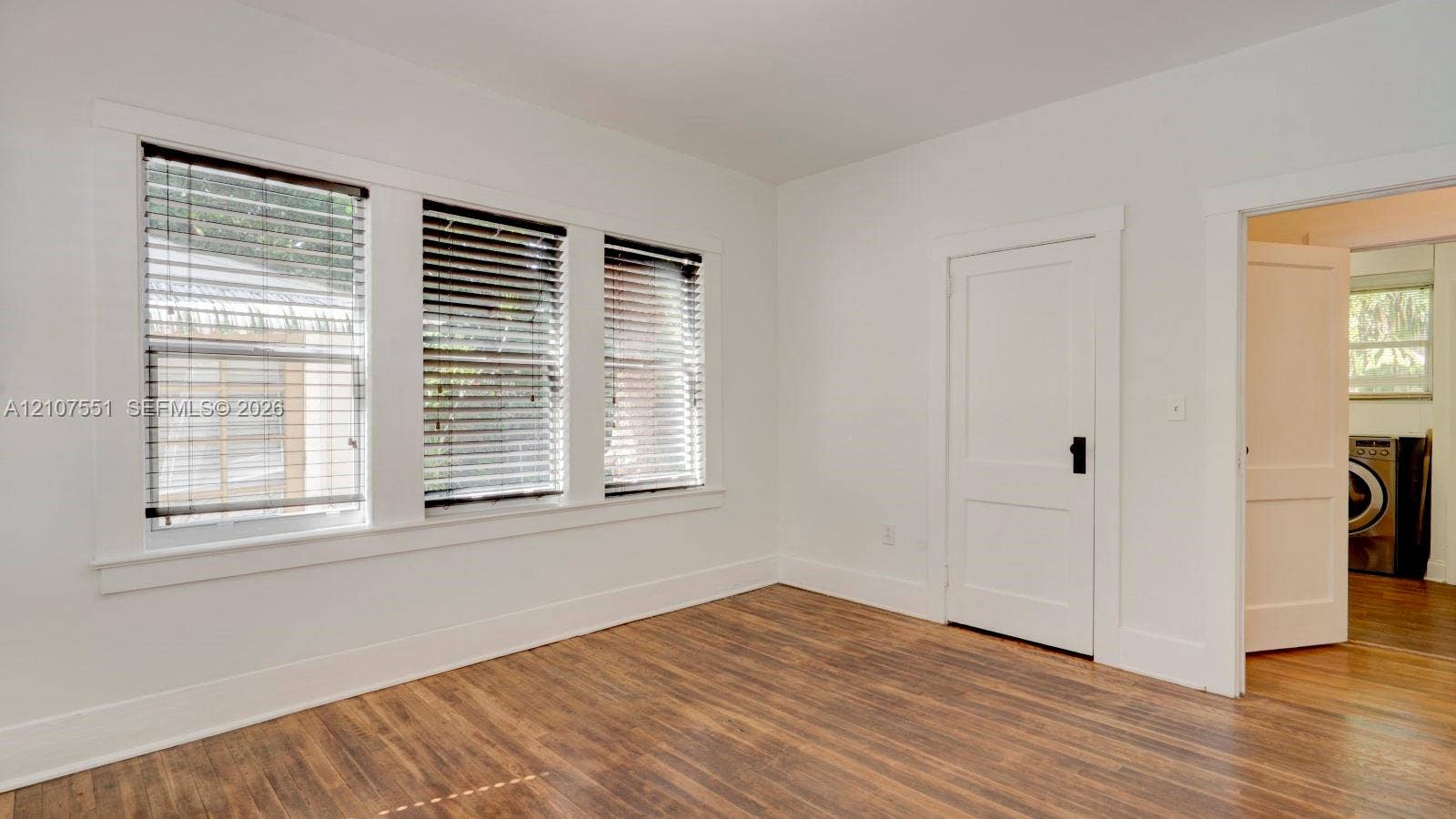 1676 SW 11th Street, Miami, Miami, FL 33135 Neutral interior featuring wood-finish flooring, white walls, and triple-pane window configuration with classic millwork trim